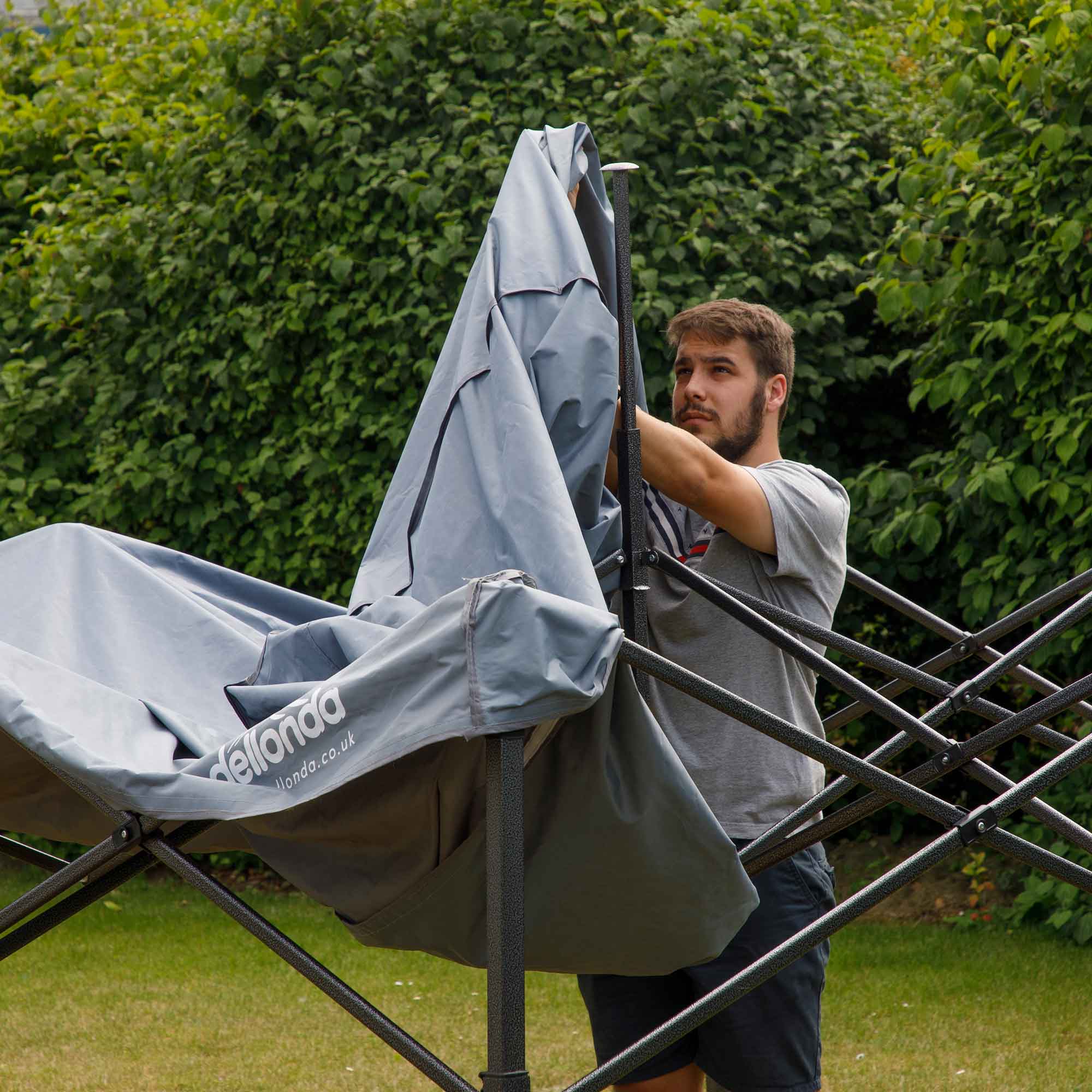 Dellonda DG129 Gazebos Action shot - putting - cover - over - 2nd perspective