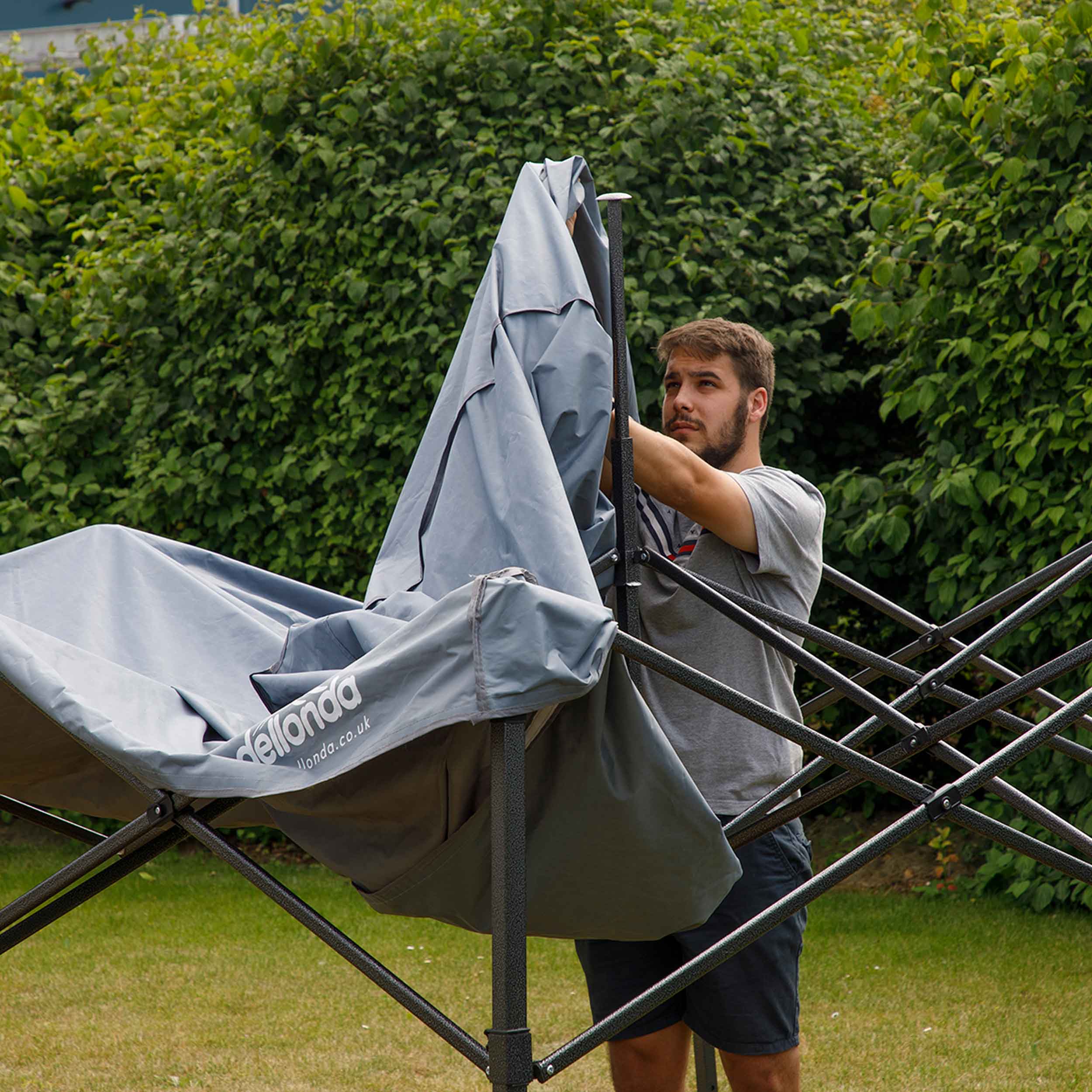 Dellonda DG133 Gazebos Action shot - putting - cover - over - 2nd perspective